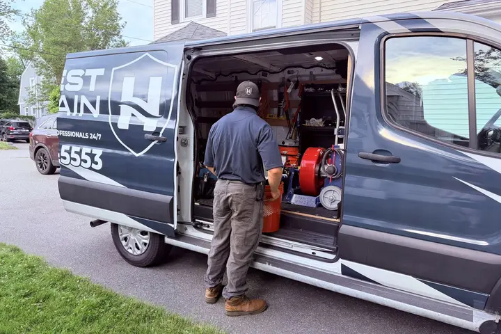 Honest Drain technician selecting drain and sewer equipment from the service van